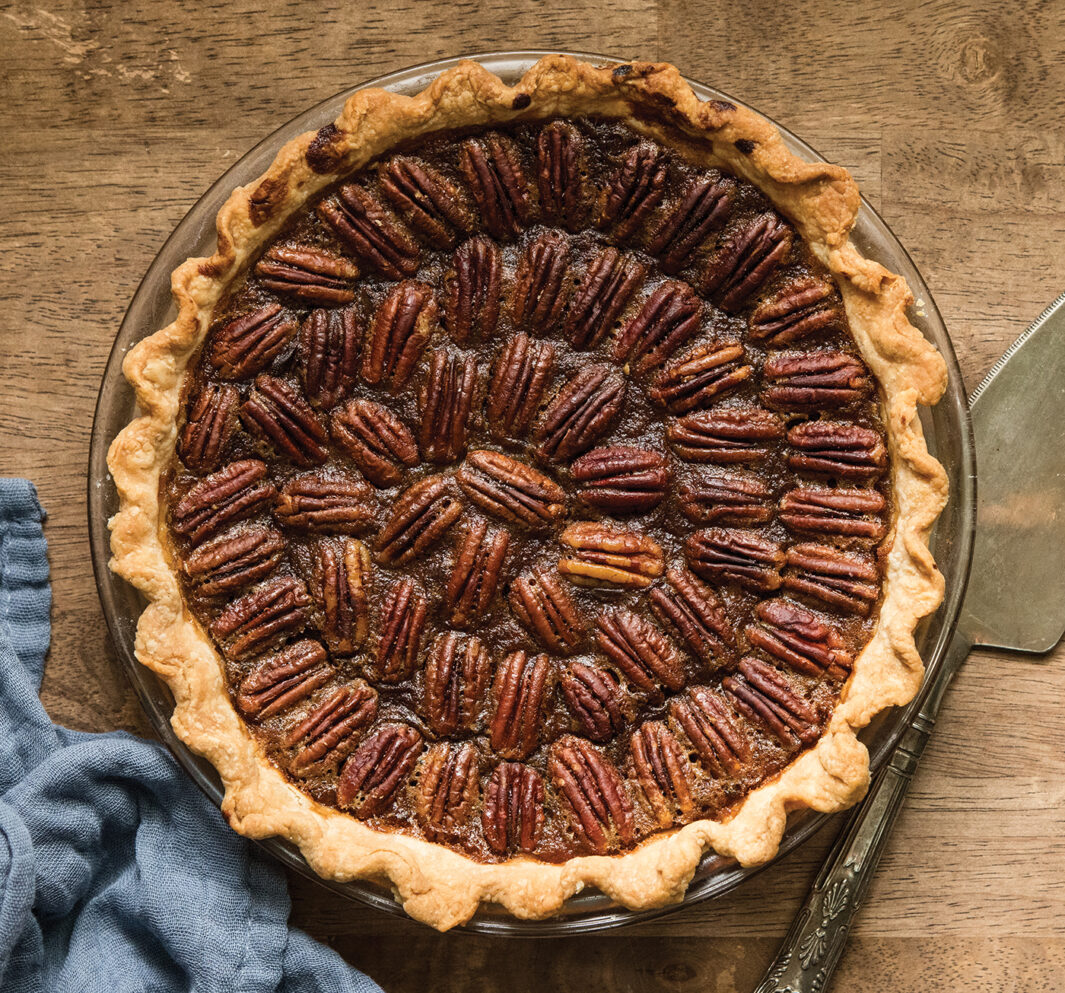 Pecan pie styled with a pie server and blue cloth